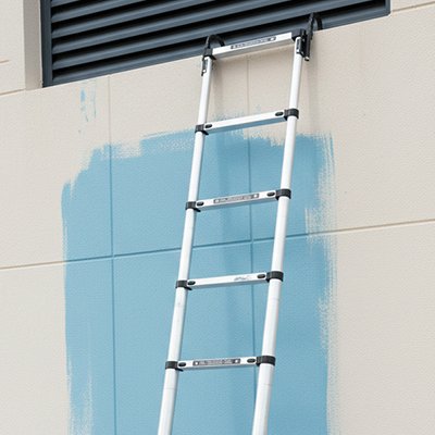 Échelle télescopique accrochée sur mur bleu