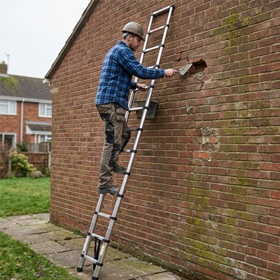 Homme répare brique sur echelle telescopique