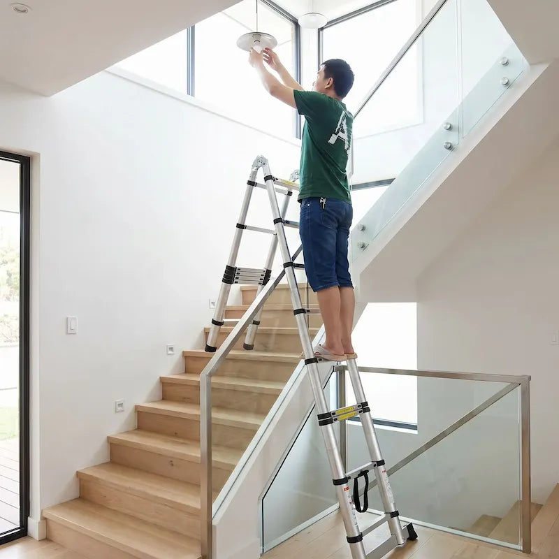 Homme change lumière cage escalier avec échelle télescopique