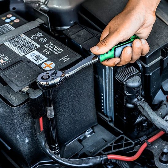 Homme installe batterie voiture avec jeu de cles a douille