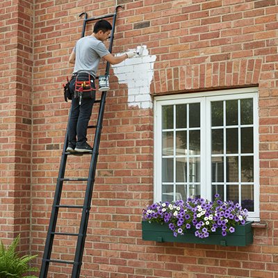 Homme peinture mur brique échelle télescopique 