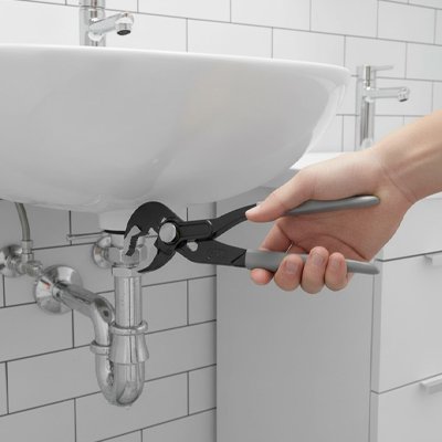 Homme répare lavabos avec grande pince multiprise 