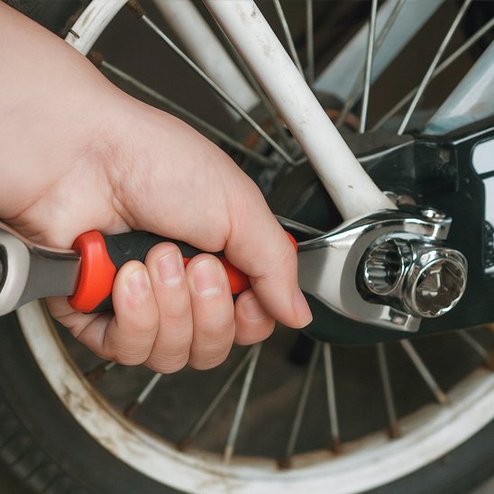 Homme utilise clé à douille pour réparer vélo