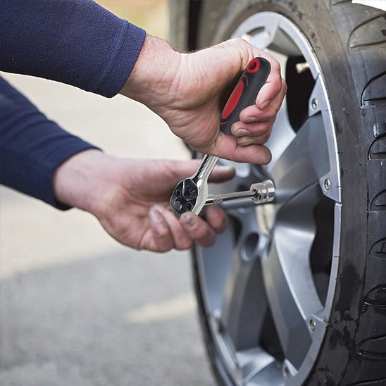Homme utilise jeu de cles a douille pour réparer roue de voiture