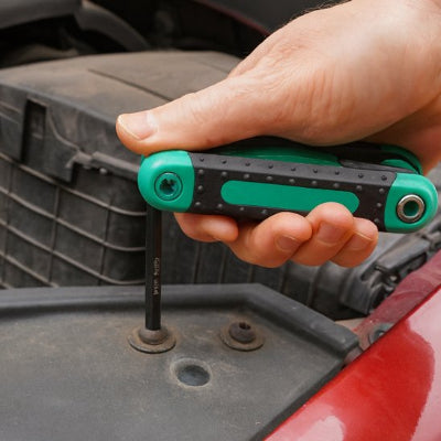 Homme utilise jeu de clés allen pour réparer voiture