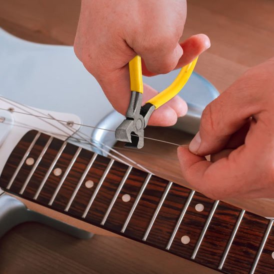 jeune-utilisant-pince-coupante-pour-arranger-guitare