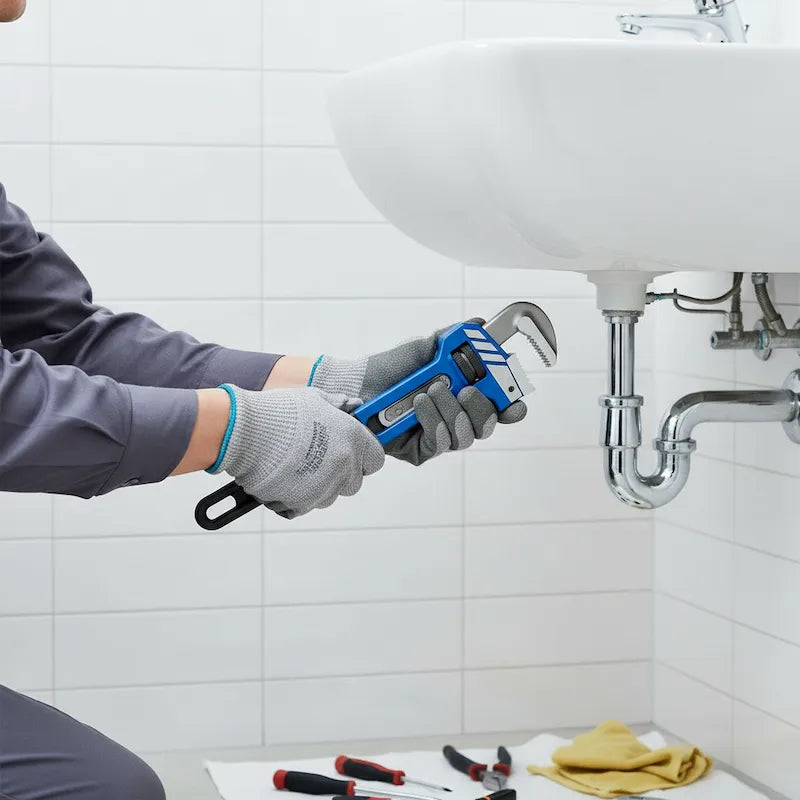 Plombier utilise clé à griffe dans salle de bain